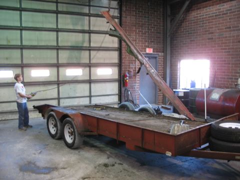1900 Ford C-350 (Centurion Conversions) - Boy controls a remote near a trailer with a metal beam being lifted in a garage.