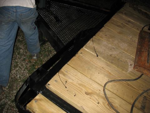 1900 Ford C-350 (Centurion Conversions) - A close-up view of a trailer ramp, showing the wooden deck and metal grating, with a person standing nearby.