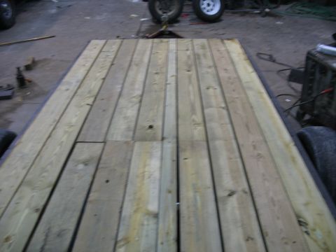 1900 Ford C-350 (Centurion Conversions) - A view of a wooden trailer deck, showing its construction and the surrounding workshop environment.
