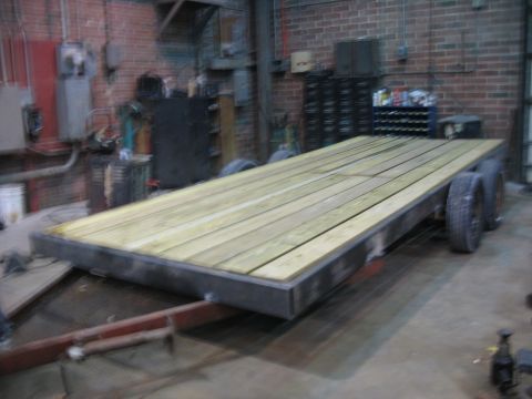 1900 Ford C-350 (Centurion Conversions) - A flatbed trailer with a newly constructed wooden deck sits in a workshop.
