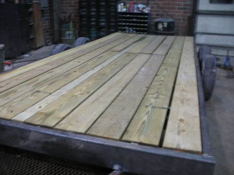 1900 Ford C-350 (Centurion Conversions) - A trailer bed constructed with wooden planks and a metal frame, seen from a side angle.