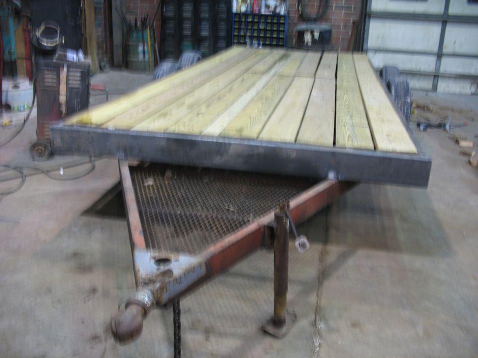 Flatbed trailer with a new wooden deck, parked indoors