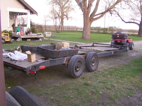1900 Ford C-350 (Centurion Conversions) - A trailer is parked in a yard, loaded with various parts and an ATV on the back.