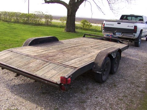 1900 Ford C-350 (Centurion Conversions) - A dual axle trailer is hitched to a white Dodge pickup truck in a gravel lot.
