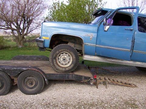 1900 Ford C-350 (Centurion Conversions) - A blue pickup truck, identified by its 'Silverado' badging, is loaded onto a trailer.