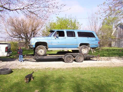 1900 Ford C-350 (Centurion Conversions) - A light blue extended cab pickup truck is being transported on a dual-axle trailer.