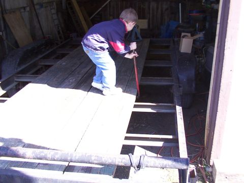 1900 Ford C-350 (Centurion Conversions) - A boy works on a trailer frame inside a garage.