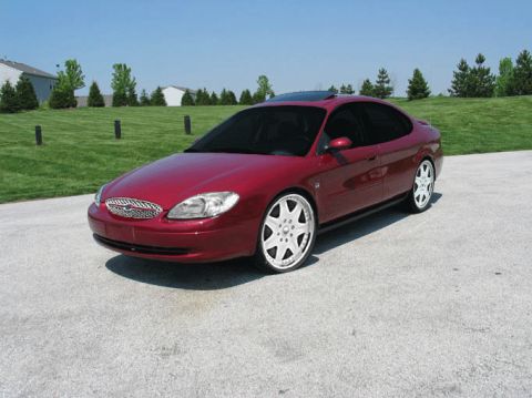 1999 Ford Taurus - A red sedan is parked outdoors on a sunny day.