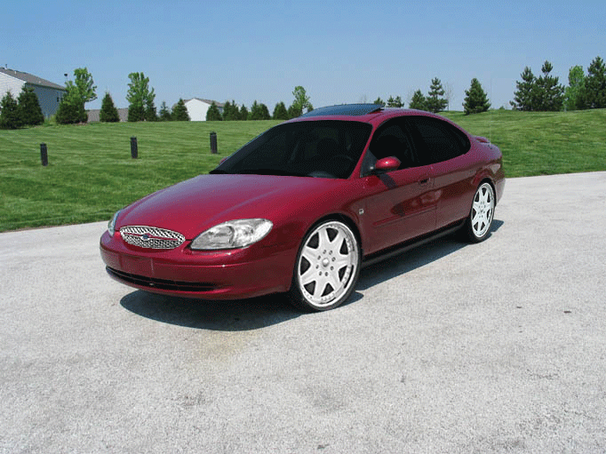 Red sedan with aftermarket wheels parked on a paved surface