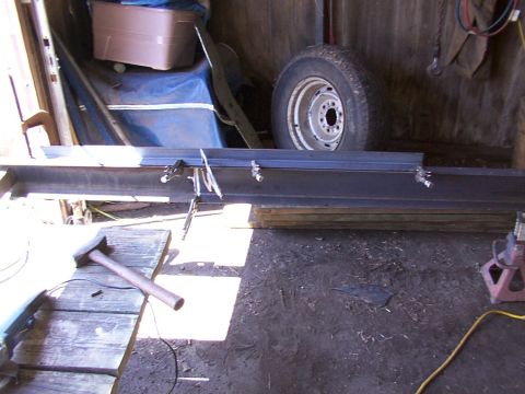1900 Ford C-350 (Centurion Conversions) - Workshop scene with steel beams, a tire, and tools, suggesting construction or repair work.