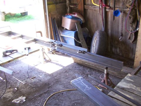 1900 Ford C-350 (Centurion Conversions) - Workshop scene with metal beams being worked on, a spare tire, and various tools and materials.