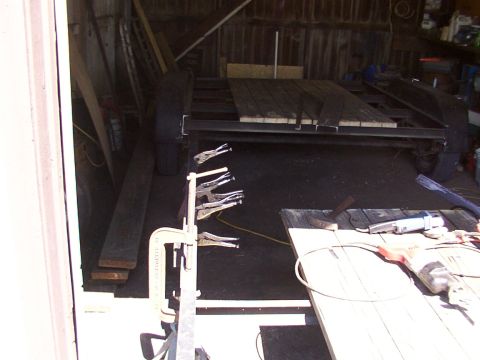 1900 Ford C-350 (Centurion Conversions) - A trailer frame is being worked on in a workshop, with tools and lumber visible.