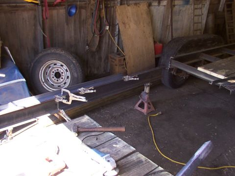 1900 Ford C-350 (Centurion Conversions) - Metal frame for a trailer is being assembled in a workshop with tools and spare tires visible.