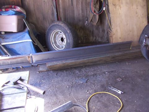 1900 Ford C-350 (Centurion Conversions) - Workshop scene with steel beams and a spare tire, possibly for a trailer or heavy equipment.