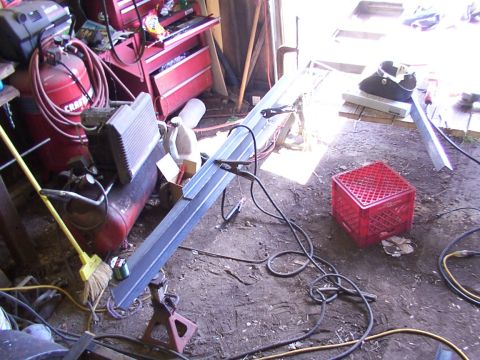 1900 Ford C-350 (Centurion Conversions) - A cluttered garage space with tools and equipment, including an air compressor and welding supplies.