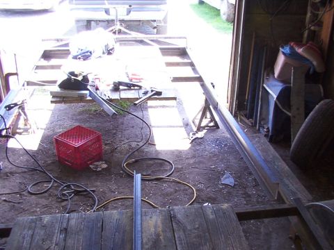 1900 Ford C-350 (Centurion Conversions) - A trailer frame is being constructed in a workshop, with welding equipment and materials scattered around.