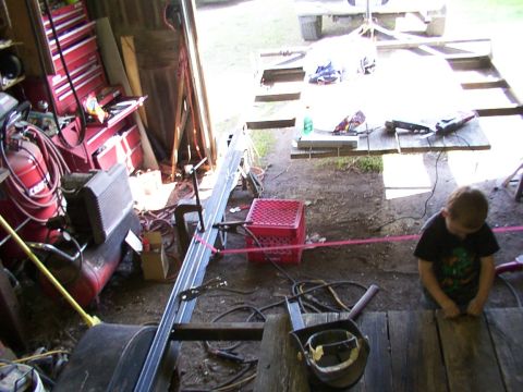 1900 Ford C-350 (Centurion Conversions) - A young child sits in a cluttered garage, surrounded by tools and equipment.