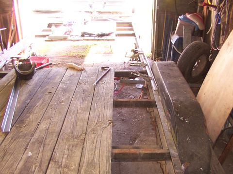 1900 Ford C-350 (Centurion Conversions) - A trailer frame is being worked on inside a garage, with tools and materials scattered around.