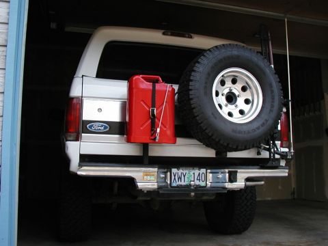 1995 Ford Bronco - A white Ford Bronco is parked in a garage, equipped with a red gas can and a spare tire on the back.