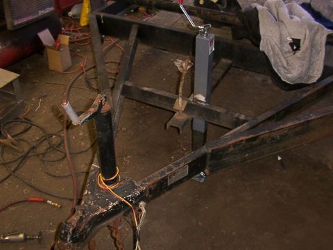 1900 Ford C-350 (Centurion Conversions) - The frame of a trailer is visible, including its hitch and a manual jack mechanism.