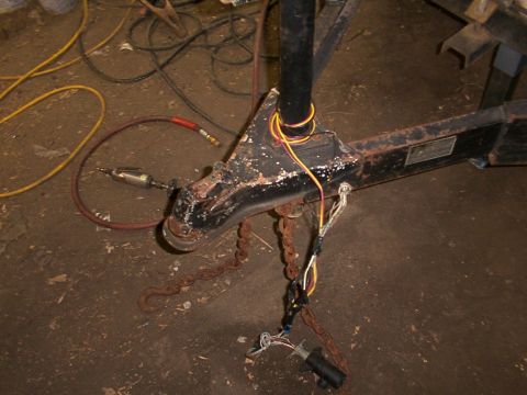 1900 Ford C-350 (Centurion Conversions) - Trailer hitch assembly with wiring harness and safety chains, with an air hose and tool nearby.