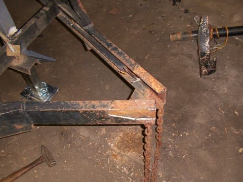 1900 Ford C-350 (Centurion Conversions) - Close-up of a trailer frame, showing a jack and chain, with a hammer on the floor.