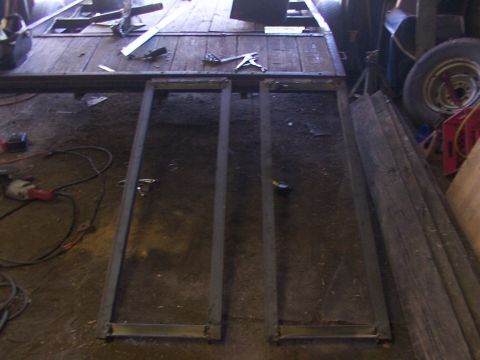 1900 Ford C-350 (Centurion Conversions) - Construction scene shows a trailer frame with metal supports and wooden planks, along with tools and a spare tire.
