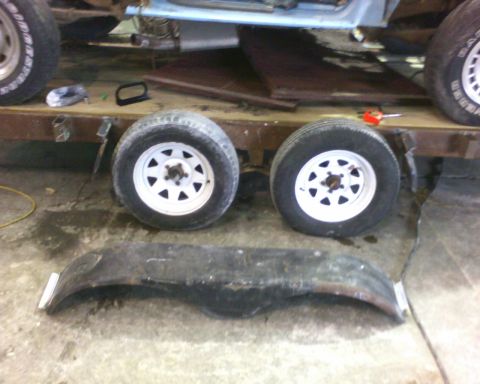 1900 Ford C-350 (Centurion Conversions) - Parts of a vehicle, including wheels and a fender, are laid out on a trailer.
