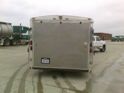 1900 Ford C-350 (Centurion Conversions) - An enclosed trailer is parked in a lot with a white pickup truck and other vehicles in the background.