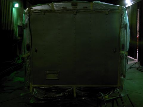 1900 Ford C-350 (Centurion Conversions) - The rear of an enclosed trailer is covered in plastic wrap, suggesting it is being prepared for transport or storage.
