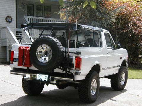 1995 Ford Bronco - Rear view of a white 1995 Ford Bronco with a spare tire and a red gas can mounted.