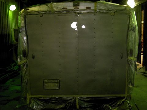 1900 Ford C-350 (Centurion Conversions) - The rear doors of a vehicle are covered in plastic sheeting, likely for protection during transport or work.