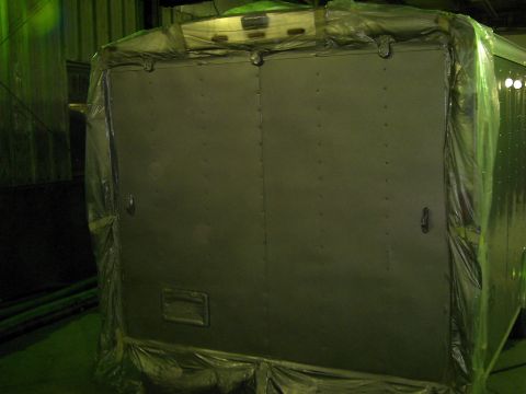 1900 Ford C-350 (Centurion Conversions) - The rear of a trailer is covered in plastic, obscuring details of its construction and model year.