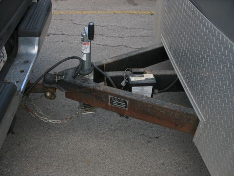 1900 Ford C-350 (Centurion Conversions) - Close-up view of a trailer hitch and coupler assembly, including safety chains and a battery box.