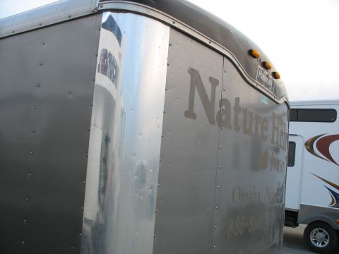 1900 Ford C-350 (Centurion Conversions) - A close-up view of an enclosed trailer, showing text and another trailer in the background.