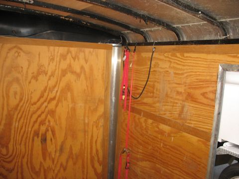 1900 Ford C-350 (Centurion Conversions) - Interior view of a trailer with tie-down straps and wood paneling visible.