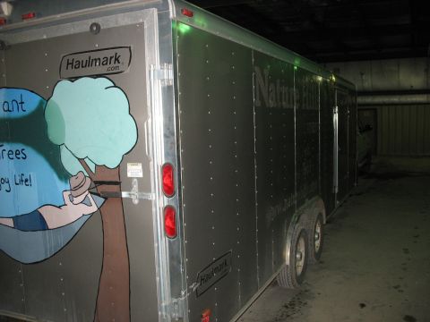1900 Ford C-350 (Centurion Conversions) - A Haulmark enclosed trailer is parked indoors, graphics of a person in a hammock and text related to Nature Hills.
