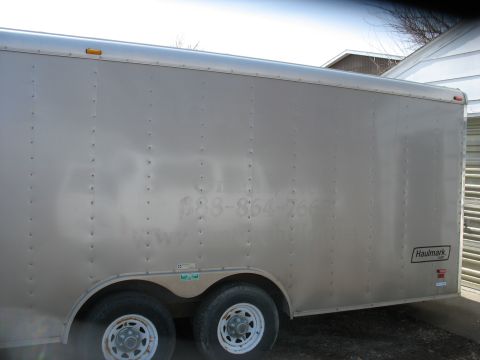 1900 Ford C-350 (Centurion Conversions) - Side view of a silver enclosed trailer with faded lettering and a Haulmark logo visible.