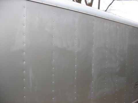 1900 Ford C-350 (Centurion Conversions) - The side of a silver trailer is shown, a pattern of rivets along its vertical seams.