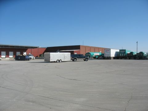 1900 Ford C-350 (Centurion Conversions) - SUV and trailer parked in front of a commercial building with other trucks nearby.