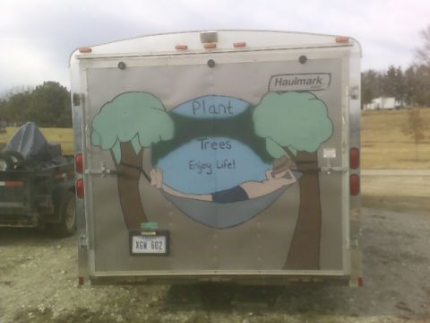 1900 Ford C-350 (Centurion Conversions) - A silver enclosed trailer with a mural and a license plate is parked next to another trailer.