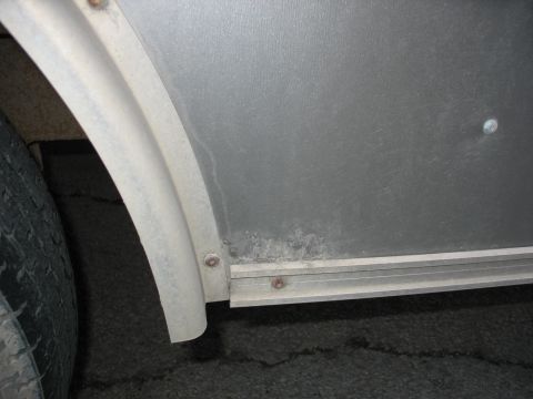 1900 Ford C-350 (Centurion Conversions) - Close-up view of a trailer's exterior, showing the wheel well and a section of the side panel.