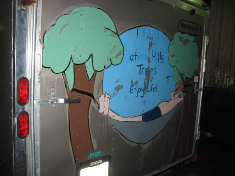 1900 Ford C-350 (Centurion Conversions) - This trailer features a mural with trees and a person relaxing in a hammock, accompanied by the text 'Nature Hills Trees Enjoy Life!'