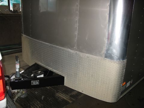 1900 Ford C-350 (Centurion Conversions) - Close-up of a trailer hitch and the lower section of a silver trailer with diamond plate accents.