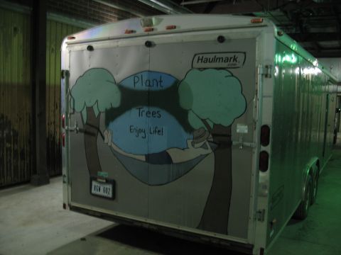 1900 Ford C-350 (Centurion Conversions) - A Haulmark trailer is parked indoors, a mural with a message about planting trees.