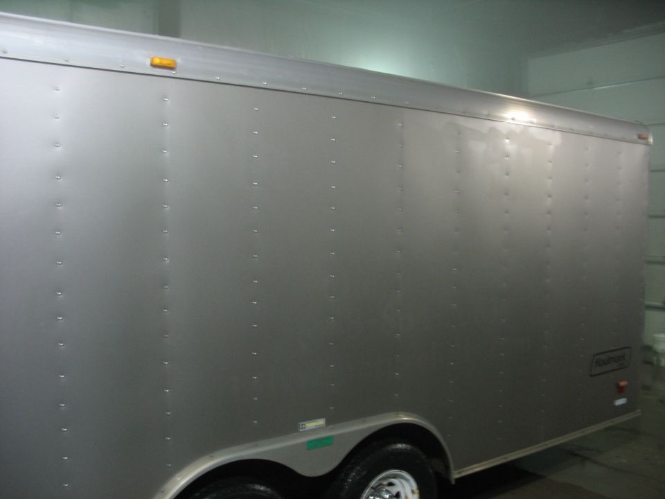 Side view of a silver enclosed cargo trailer with rivets and amber marker lights