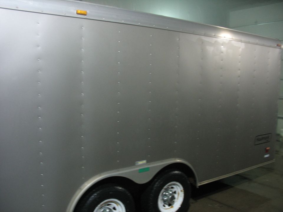 Side view of a silver enclosed cargo trailer with tandem axles and white wheels