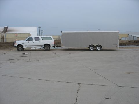 1900 Ford C-350 (Centurion Conversions) - A white Ford Bronco SUV is seen from the side, towing a large silver enclosed trailer.