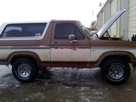 1985 Ford Bronco - Side view of a 1985 Ford Bronco in brown and white, with its hood open.