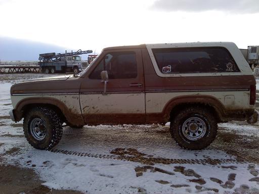 1985 Ford Bronco side view, brown and white two-tone paint, muddy